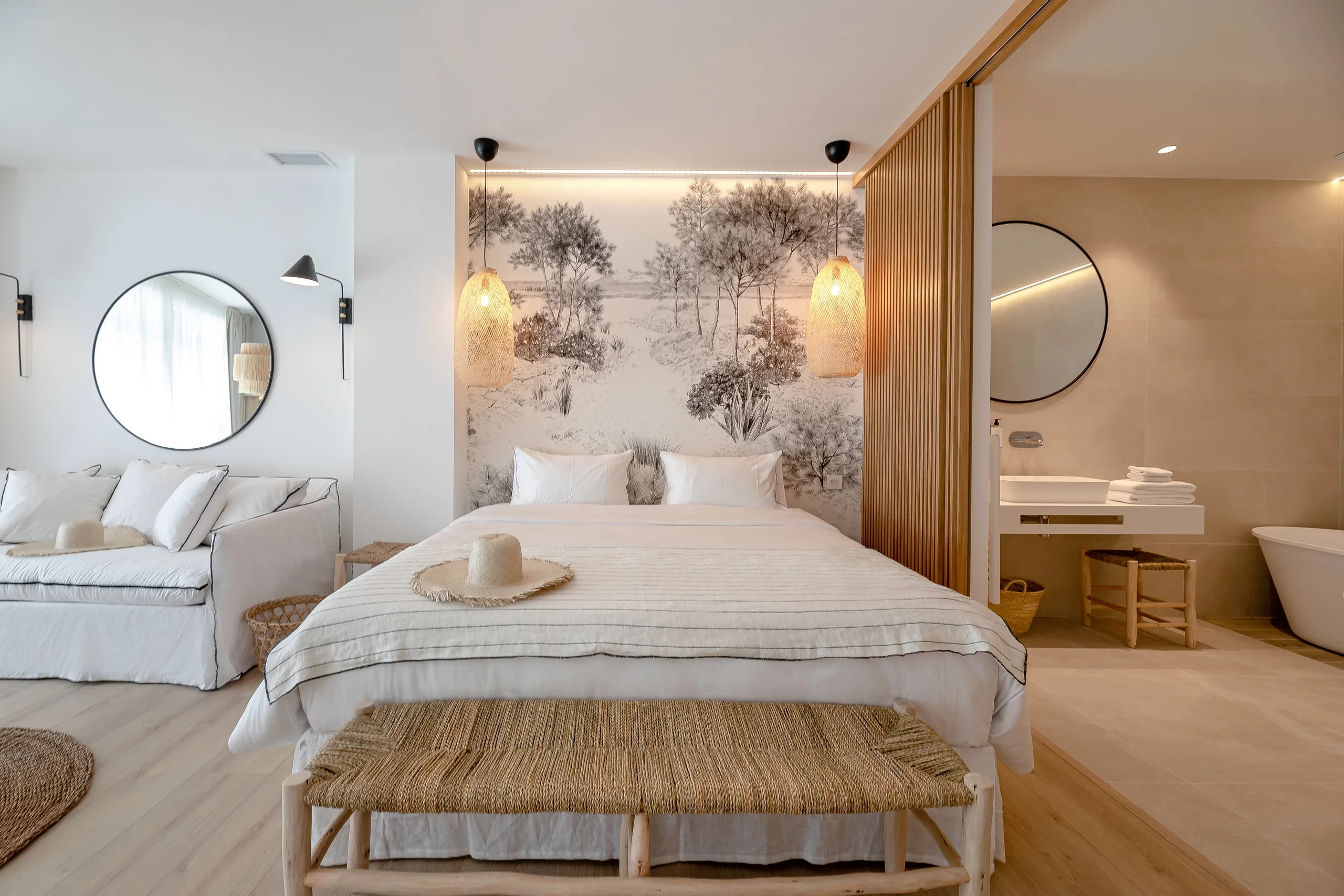 Chambre moderne avec fresque murale végétale lit double fait et banc en bois au pied - Location Appartement Perpignan - Les Suites Collection