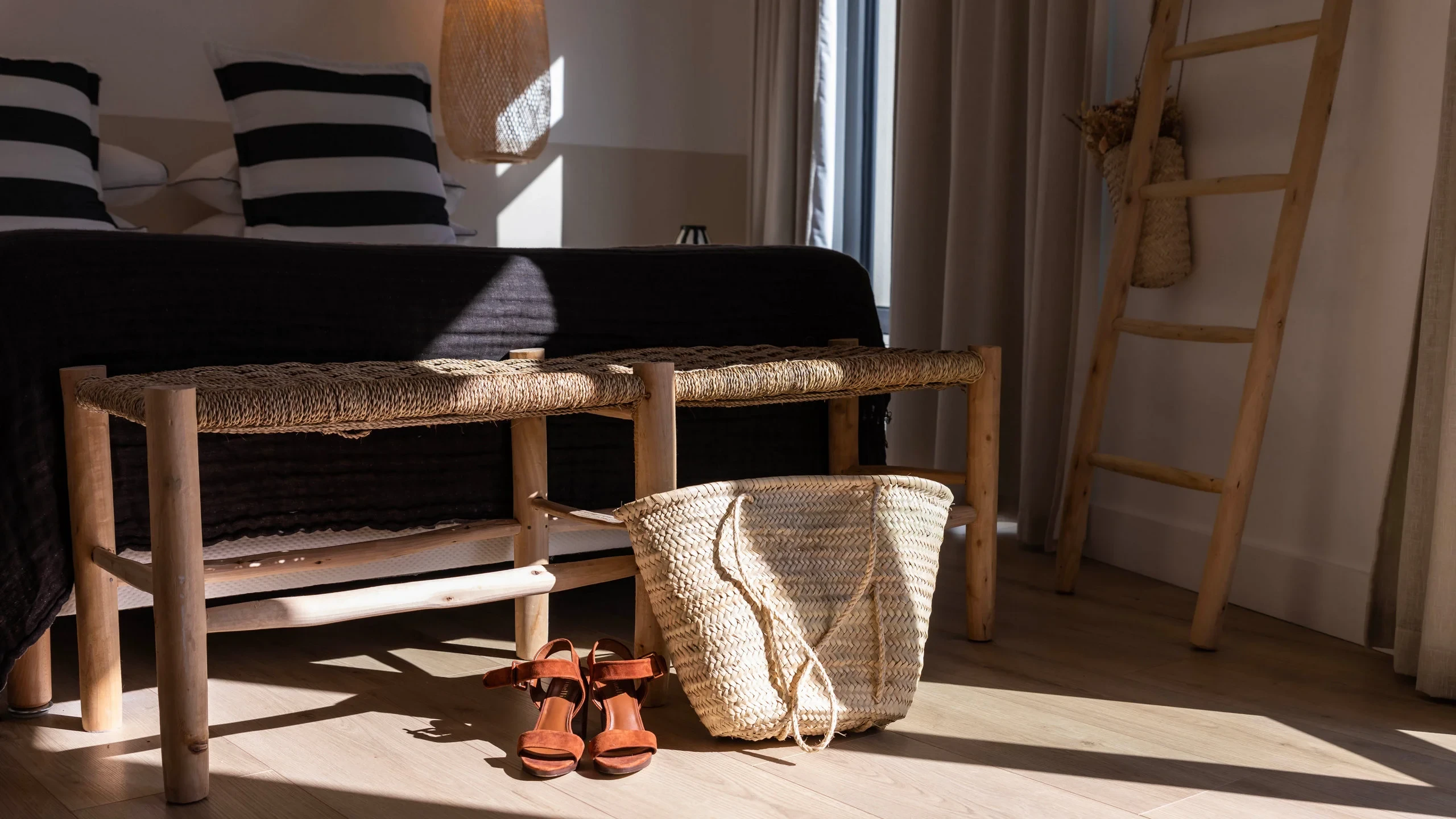 Sac de plage en paille et sandales posés devant une table basse en bois naturel - Appartement Vacances Perpignan - Les Suites Collection