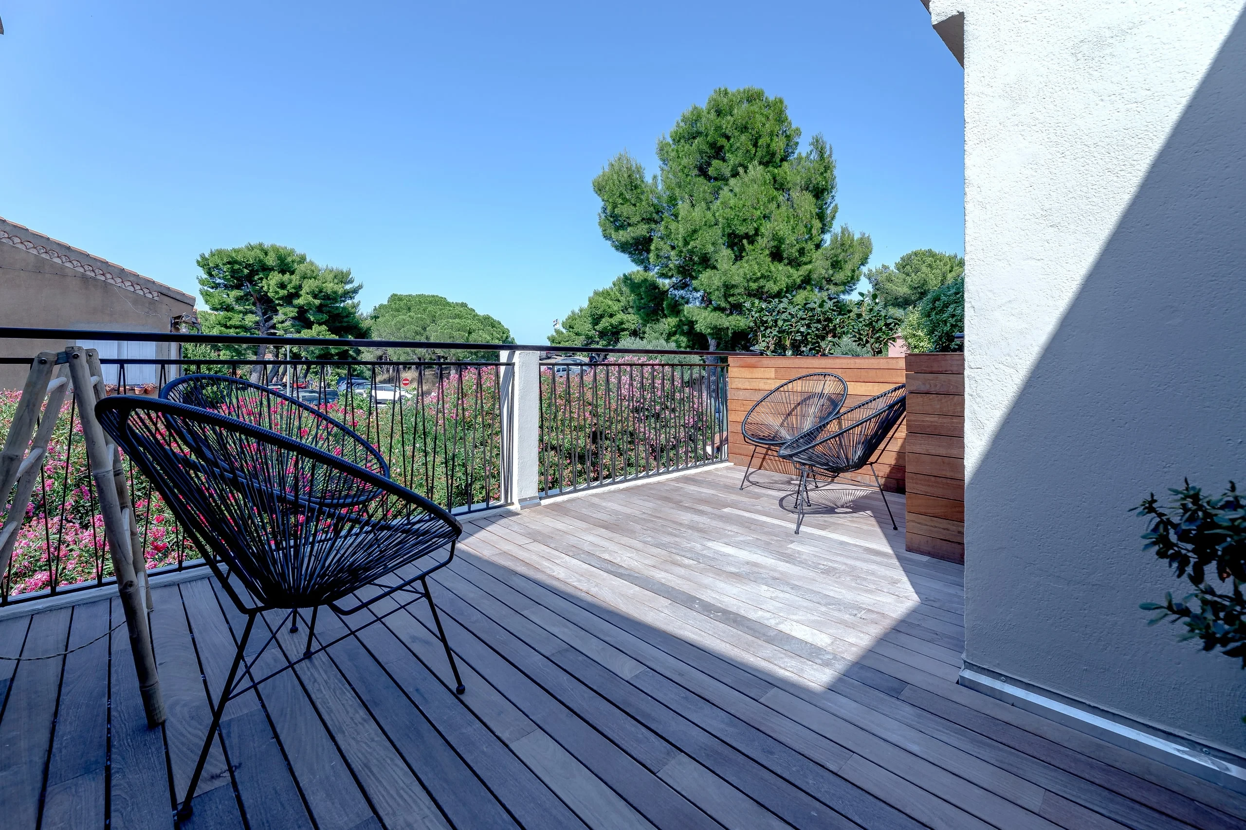 Terrasse privative en bois avec fauteuils modernes sous le ciel bleu - Location Appartement Perpignan - Les Suites Collection
