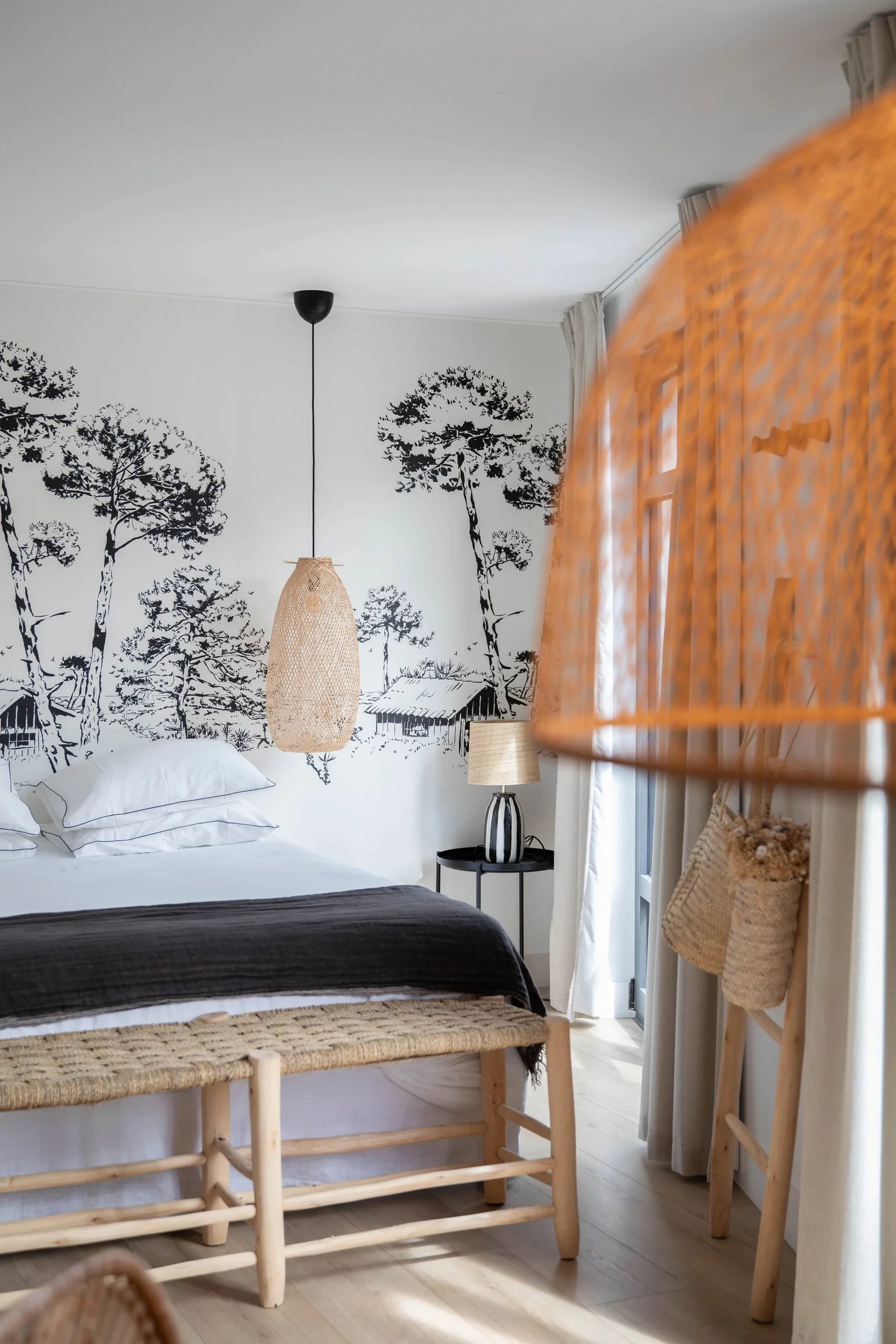 Chambre élégante décorée d'une fresque murale végétale et d'une suspension naturelle - Location Appartement Perpignan - Les Suites Collection